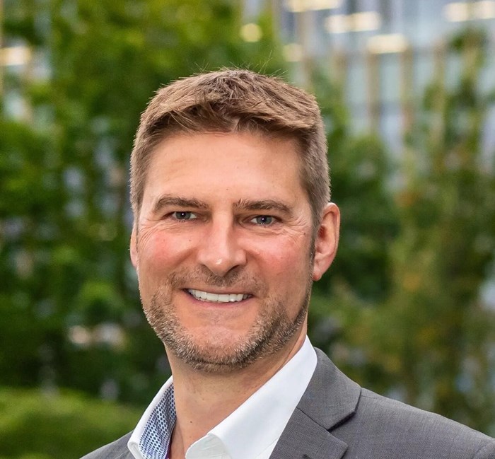 A headshot of a man looking down the camera lens