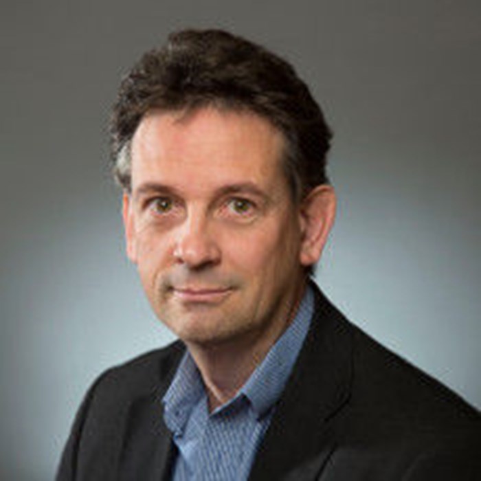 A headshot of a man looking down the camera