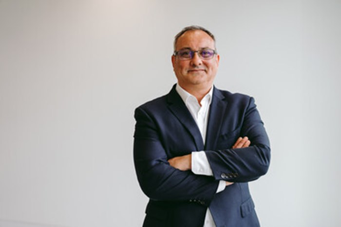 A headshot of a man with his arms folded looking towards the camera