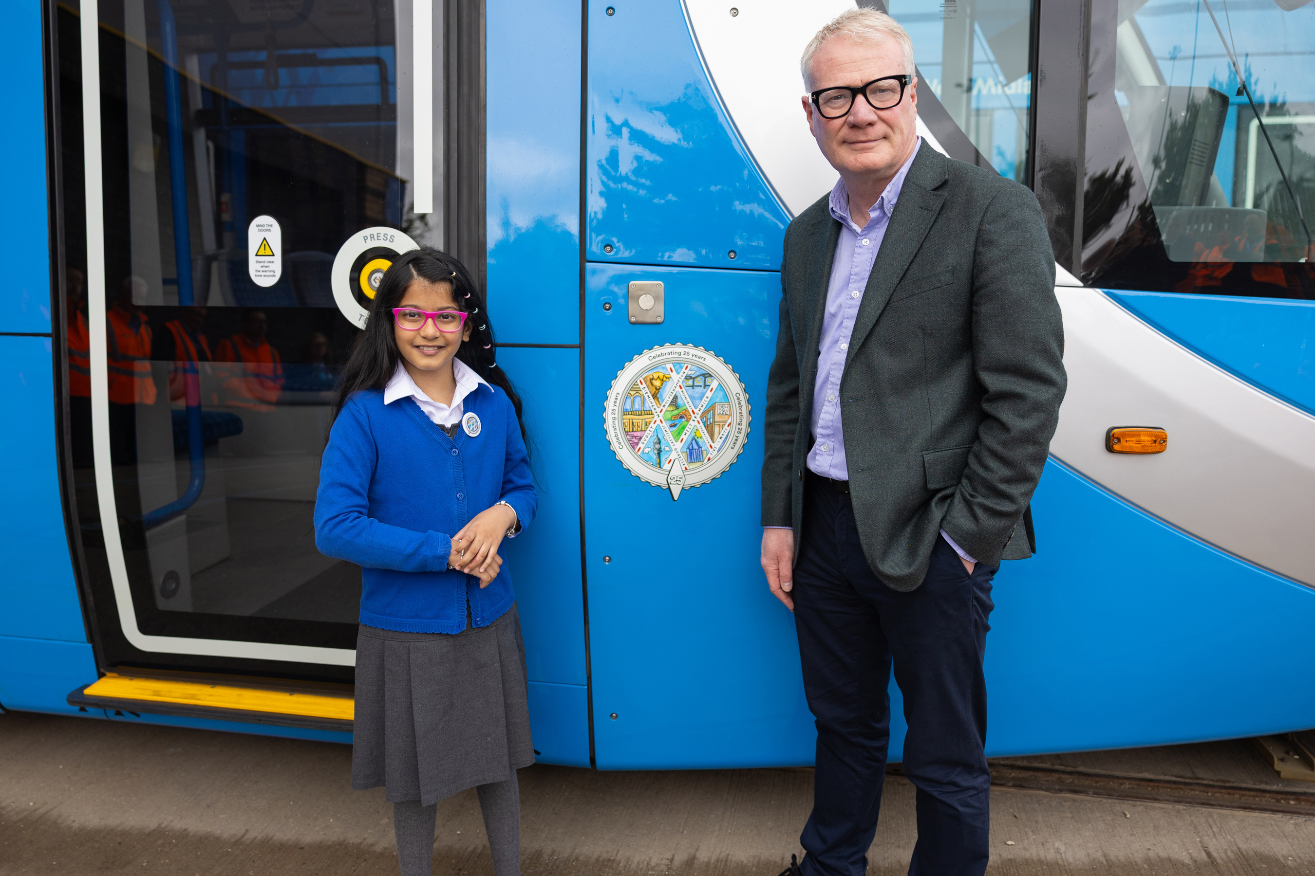 Pargunn Kaur Birring with West Midlands Mayor Richard Parker after unveiling the new logo on the side of a blue West Midlands Metro tram
